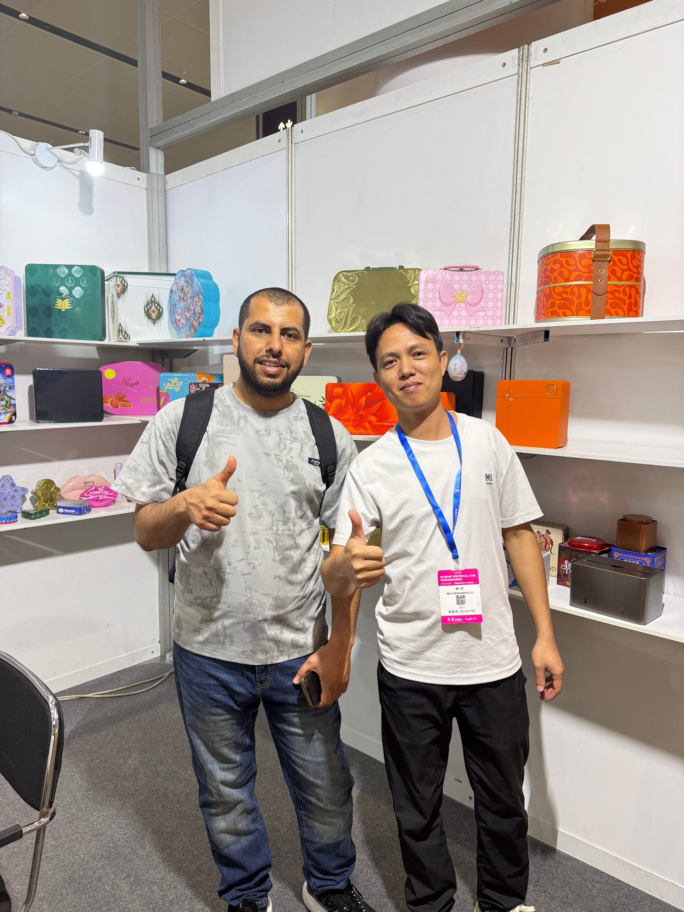 Junmei representative and overseas buyer reviewing tin box samples at an exhibition